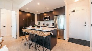 A modern kitchen with dark wood cabinets, stainless steel appliances, and a central island with bar stools.