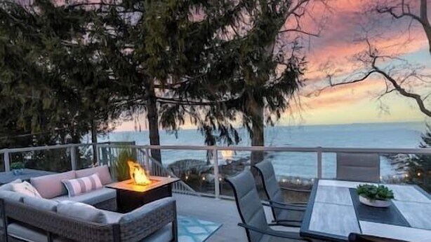 Eine Terrasse mit einer Sitzecke, einem Tisch und einem Feuerelement.