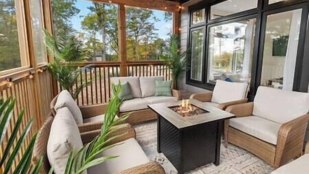 A covered outdoor seating area with wicker furniture and a central fire feature. - Northern Lights Muskoka w/ Hot Tub & Pool Table (Muskoka District Municipality)