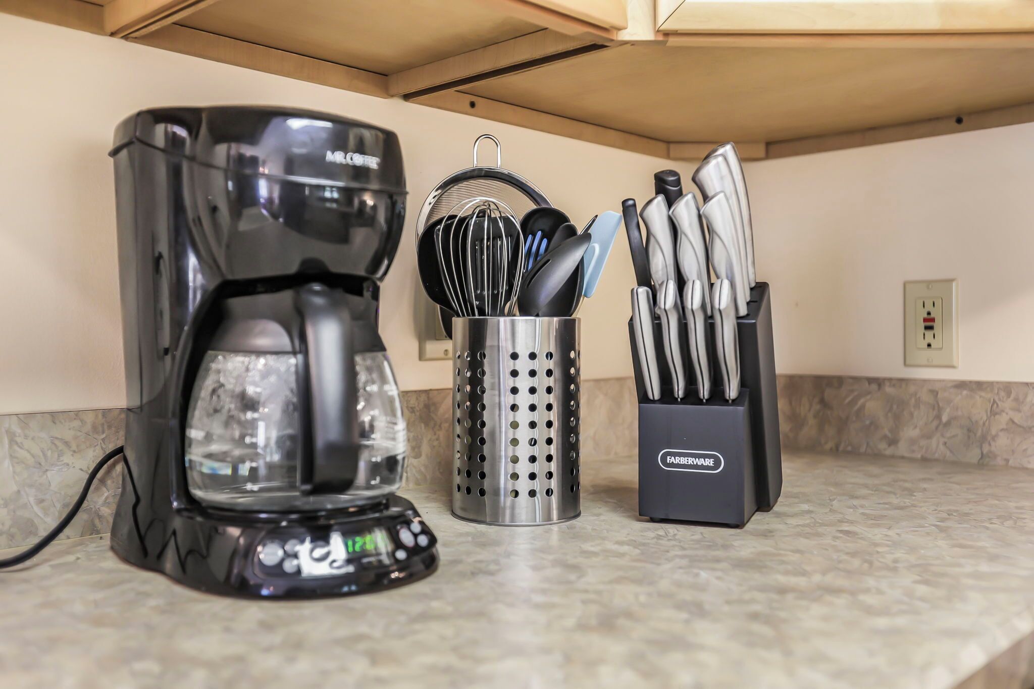 A kitchen with a coffee maker, a utensil holder, and a knife block.