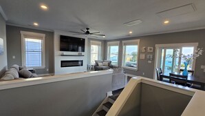Un salon moderne doté d’une cheminée, d’un ventilateur de plafond et d’un coin repas avec une table et des chaises.