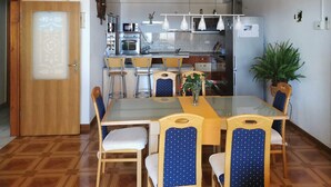 A dining area with a glass table, blue chairs, and a kitchen in the background. - Amazing apartment in Omis (Omis)