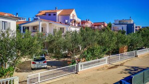 A residential area with houses, a car parked in front, and a white fence. - Amazing apartment in Vodice with WiFi (Vodice)