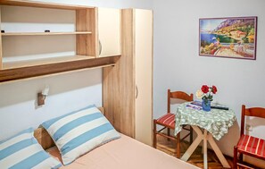 A bedroom with a bed, a wooden wardrobe, a small table with chairs, and a painting on the wall. - 1 bedroom lovely apartment in Vodice (Vodice)