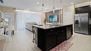 Uma cozinha moderna com ilha central, eletrodomésticos de aço inoxidável e iluminação pendente.