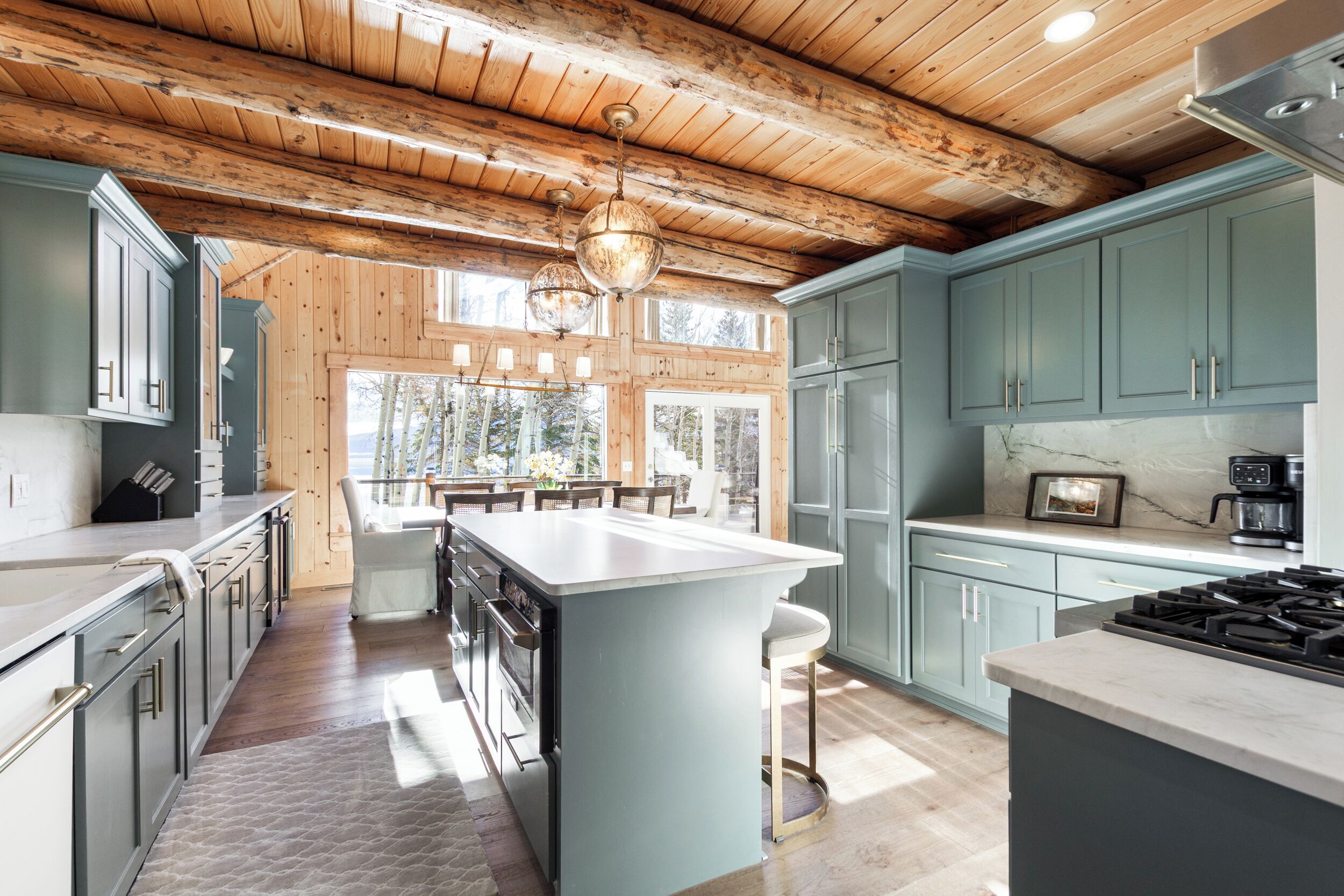 A modern kitchen with wooden beams, light blue cabinets, and a central island.