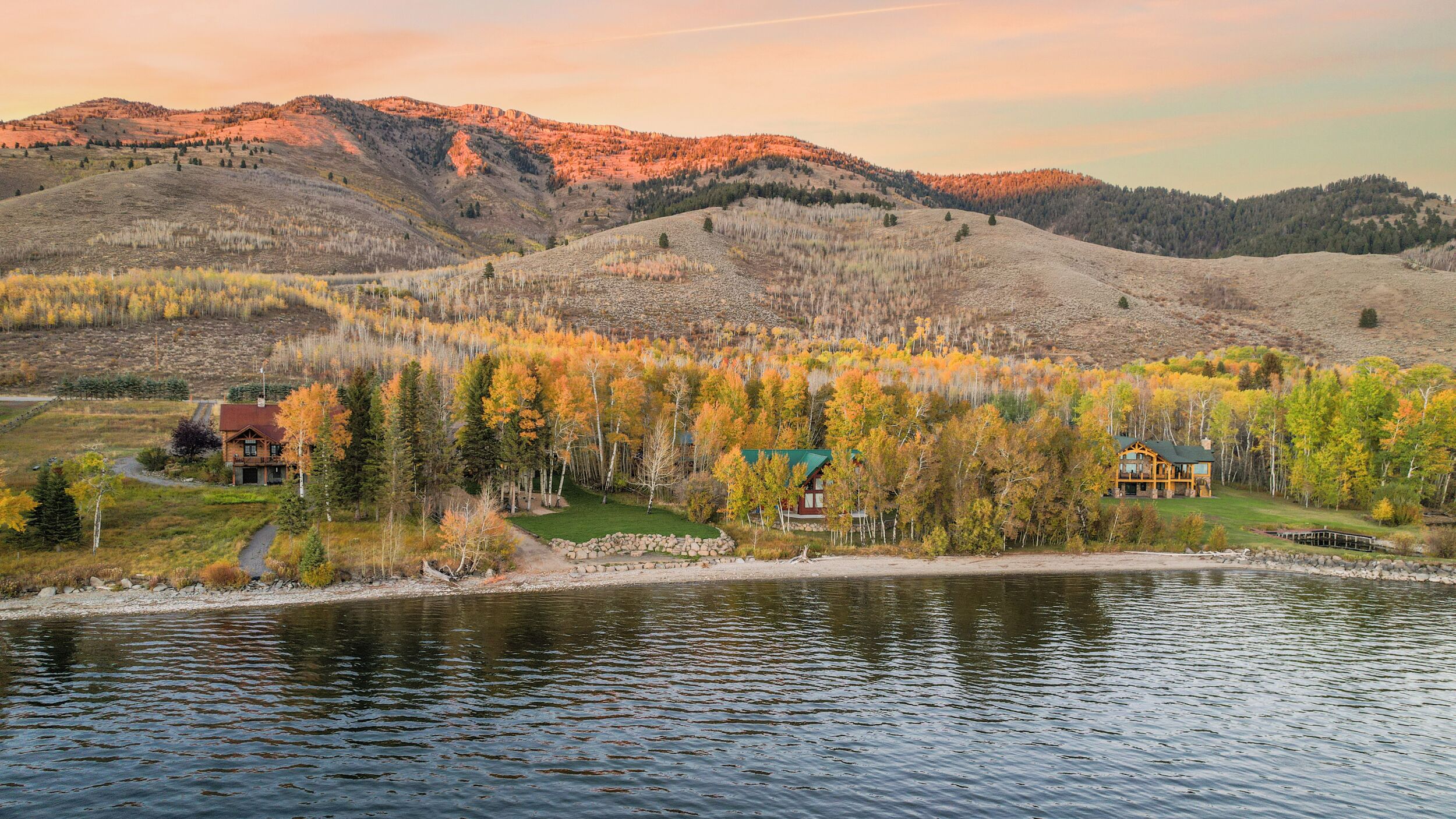 A lakeside cabin with a view of the surrounding forest and mountains.