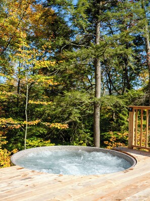 Jacuzzi sobre un pont de fusta envoltat d'arbres.