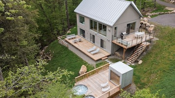 Une maison moderne dotée d’une terrasse, d’un espace salon extérieur et d’un jacuzzi.