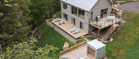 Una casa moderna con terraza, asientos exteriores y un jacuzzi.