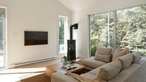 Una sala de estar moderna con un ventanal grande, chimenea, televisor de pantalla plana y un sofá cómodo.