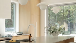 Una cocina moderna con una isla grande, taburetes blancos y lámparas colgantes.