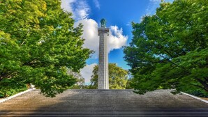 Monumentti, jossa on korkea pylväs ja siihen johtavat portaat, ja sen ympärillä on puita.
