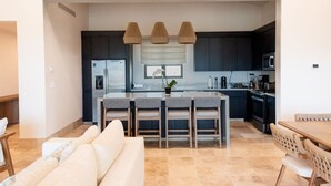 Een moderne keuken met donkere kasten, een centraal eiland met barkrukken en hanglampen.