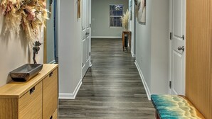 A hallway with a wooden bench, a decorative wall piece, and a ceiling light fixture. - New & Modern Home in Southport • Family & Pet Friendly (Southport)