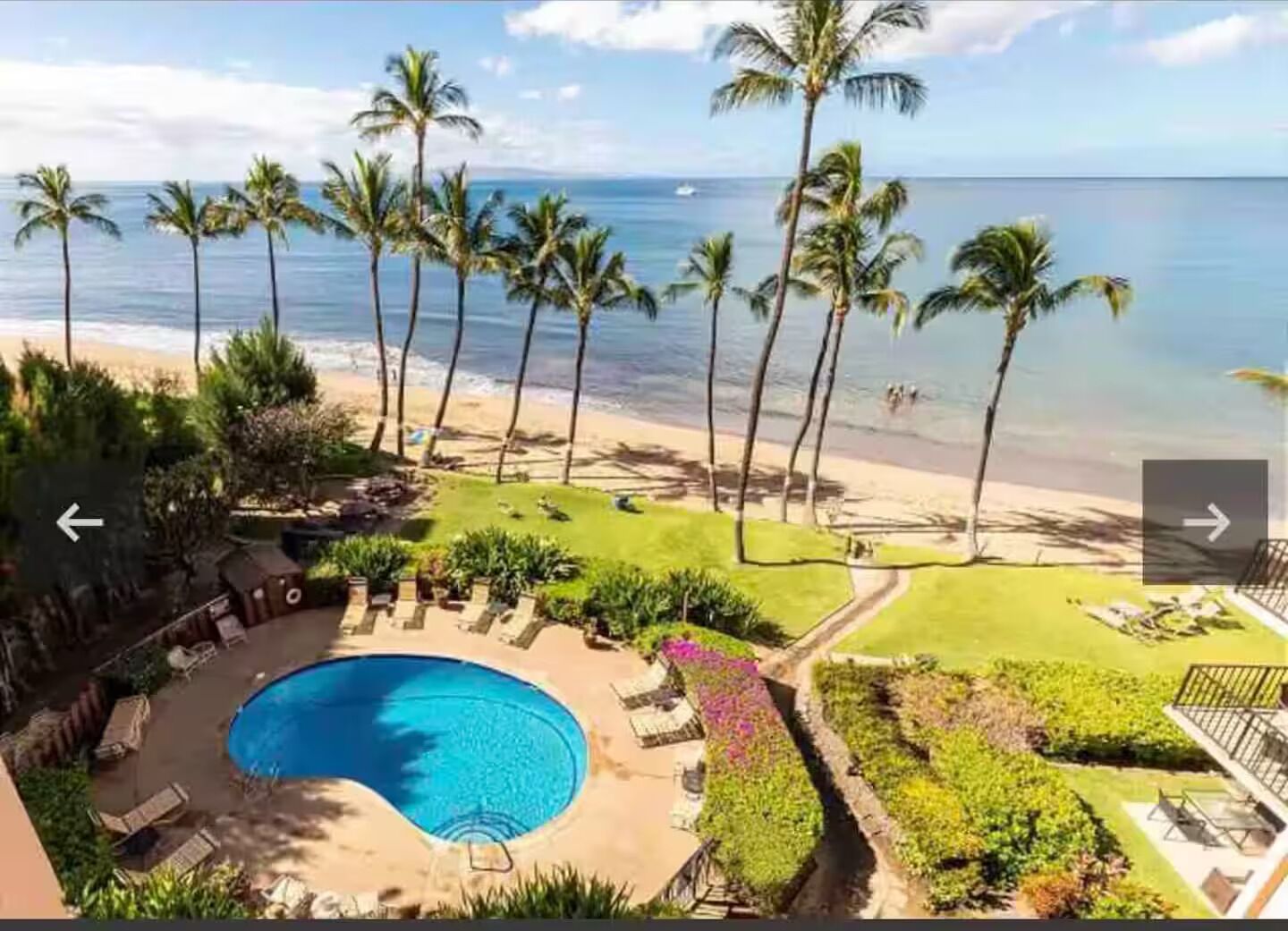 A pool area with a circular pool, surrounded by lounge chairs and a small deck.
