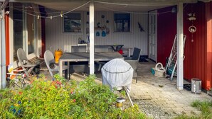 A covered outdoor area with a table and chairs, a grill, and a gas cylinder. - 2 bedroom beautiful home in Orø (Orø)