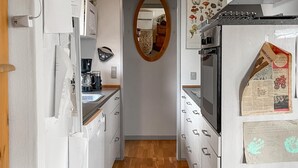 A narrow kitchen with white cabinets, a coffee machine, and a microwave. - 2 bedroom beautiful home in Orø (Orø)