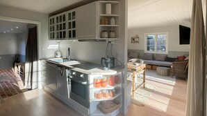 A modern kitchen with a central island, built-in cabinets, and a dining area with a sofa and table. - Beautiful home in Nykøbing Sj with sauna (Nykøbing Sj)