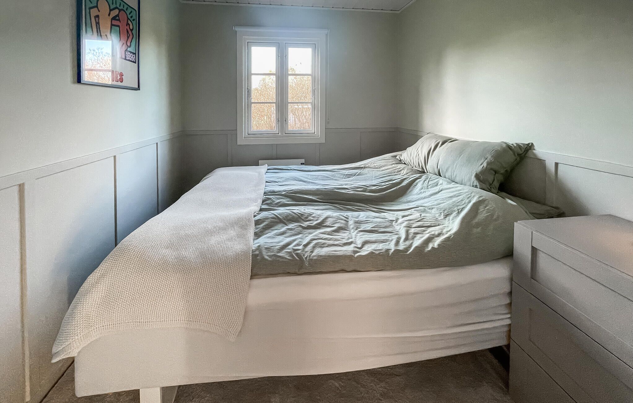 A bedroom with a bed, a window, and a dresser.