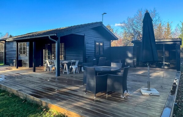 A wooden deck with outdoor furniture, a covered patio area, and a small building with windows. - Beautiful home in Nykøbing Sj with sauna (Nykøbing Sj)