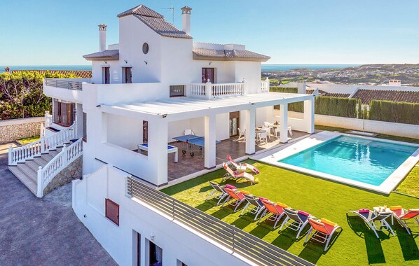 Una casa moderna de dos pisos amb piscina, mobiliari d'exterior i vistes a la natura.