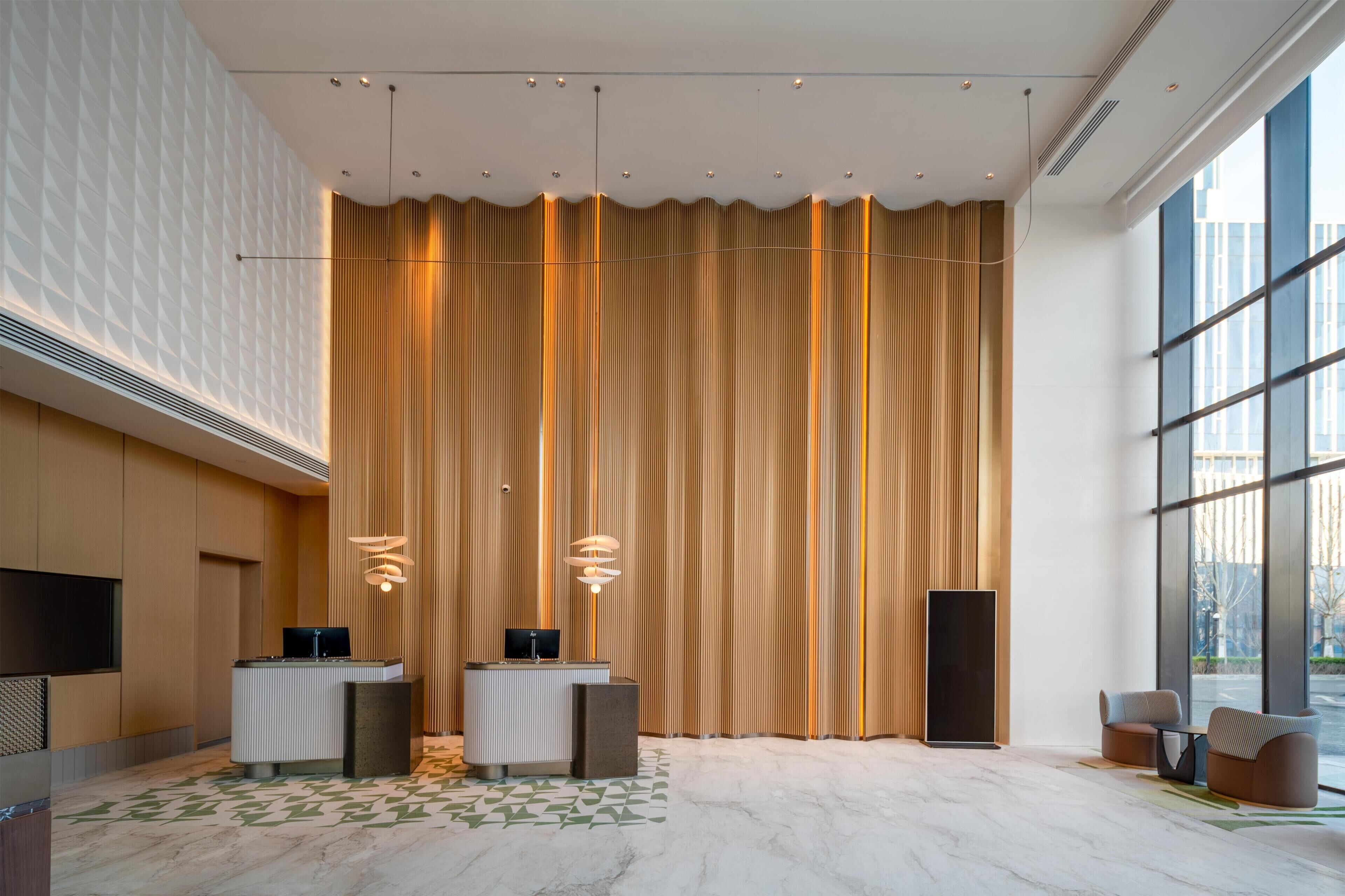 Un área de recepción moderna con un amplio muro cortina, un mostrador de recepción, zona de estar y un gran ventanal con vistas al exterior.