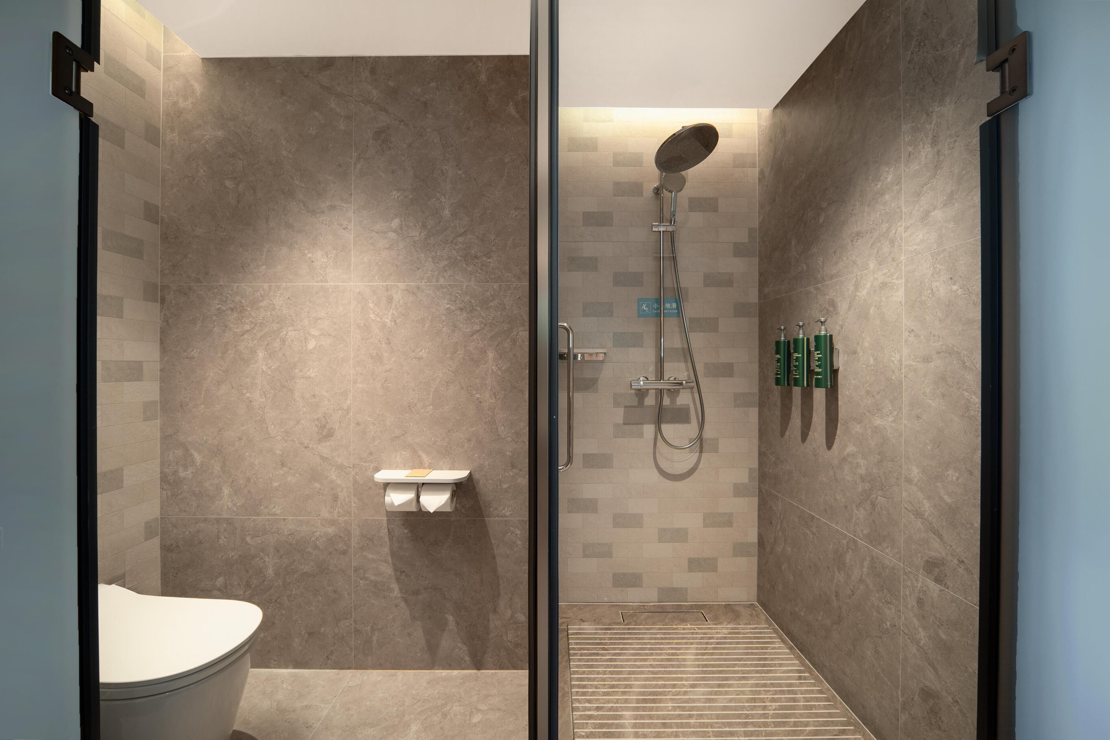 A modern bathroom with a glass-enclosed shower, a toilet, and a sink.