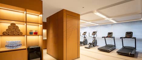 Un gimnasio moderno con equipo de ejercicio, dispensador de agua y toallas ordenadas.