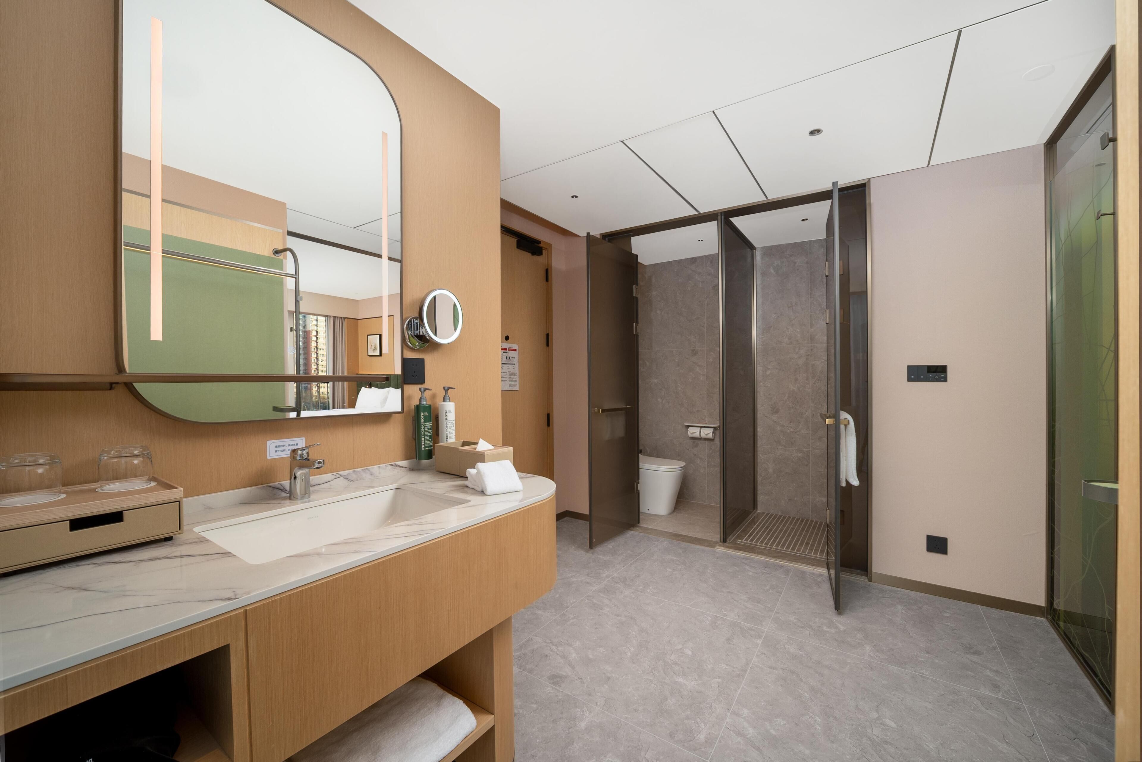 Un baño moderno con un espejo grande, un lavabo y una zona de ducha.