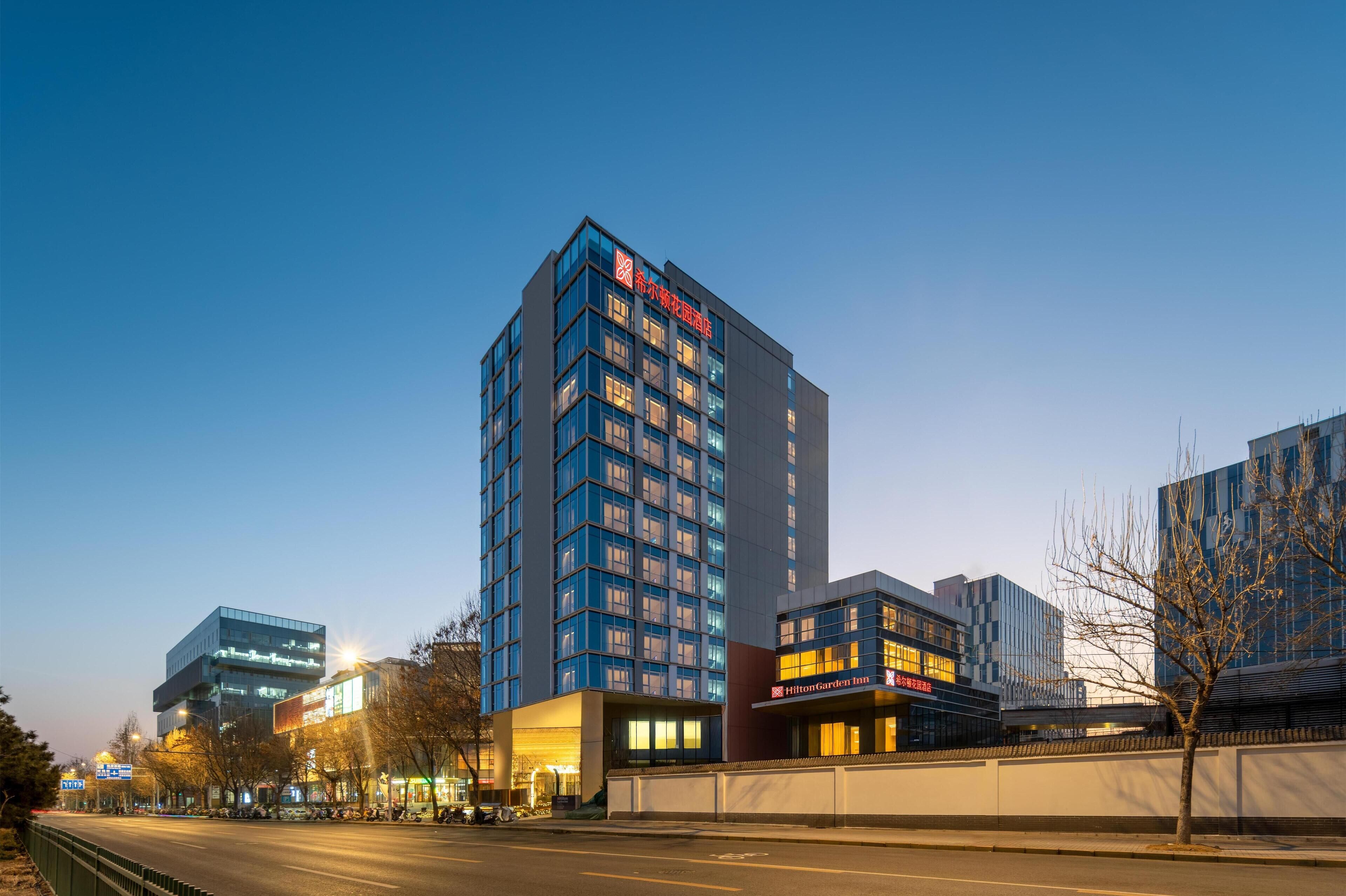 Un moderno edificio de hotel con varios pisos, ventanas amplias y un letrero llamativo.