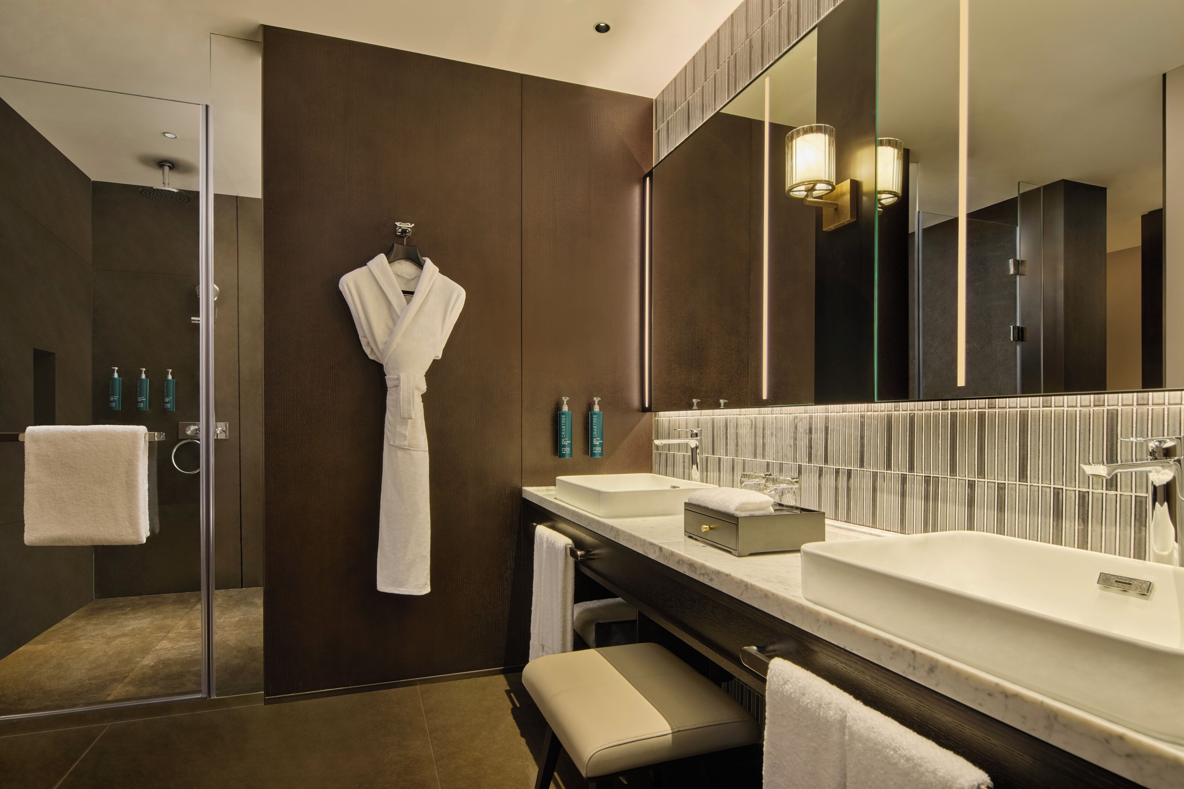 A modern bathroom with a glass-enclosed shower, a large mirror, and a vanity with a sink and countertop.