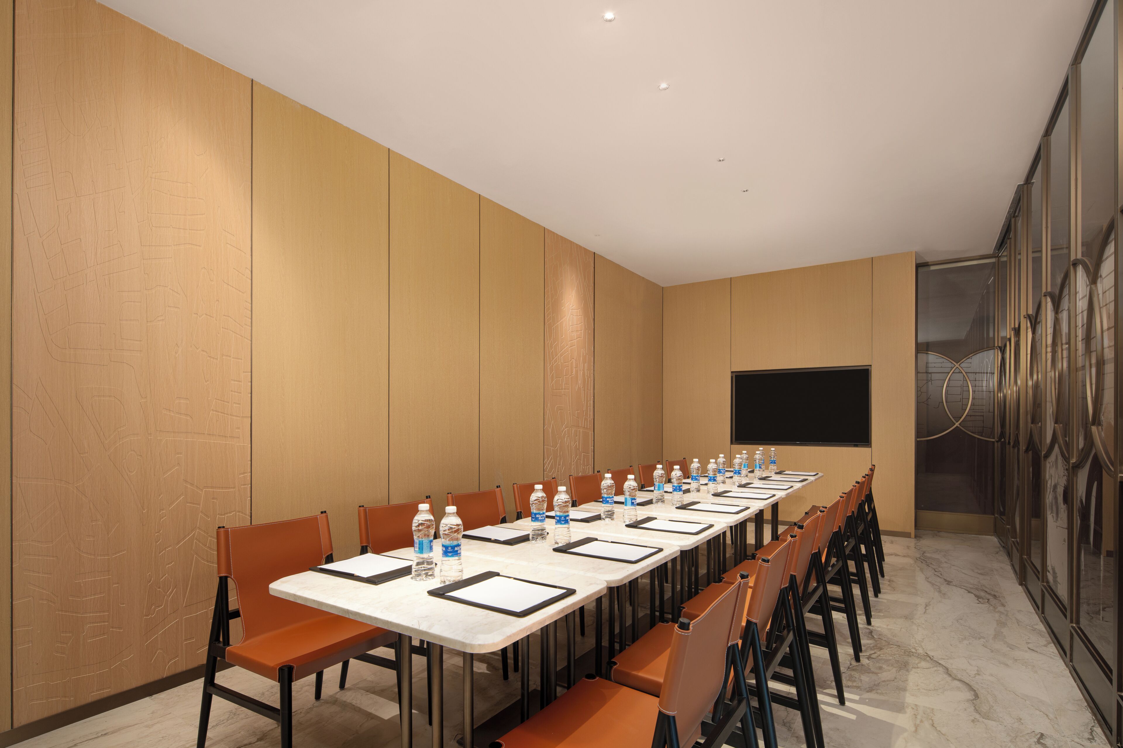 A conference room with a long table, chairs, water bottles, and a projector screen.