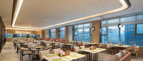 A spacious restaurant with high ceilings, large windows, and a variety of seating arrangements including tables and booths.