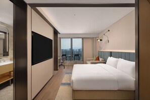 A hotel room with a large bed, a TV, a desk, and a balcony with chairs. - Hilton Garden Inn Hangzhou Fuyang Fuchun (Hangzhou)