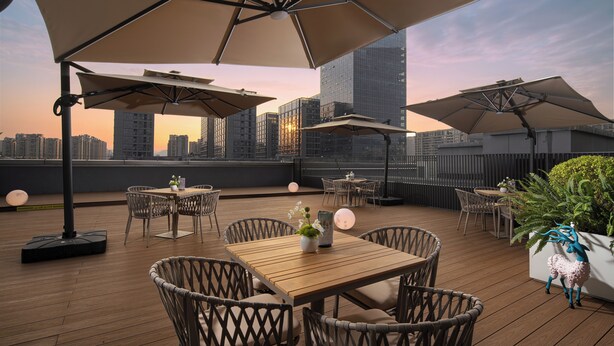 Terraza en la azotea con mobiliario exterior, sombrillas y vistas al horizonte de la ciudad.