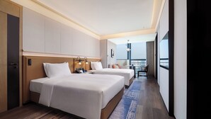 Una habitación de hotel con dos camas, un escritorio y vistas a la ciudad.