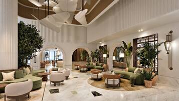 A spacious lobby with a central seating area, multiple sofas, and a large arched doorway leading to another room.
