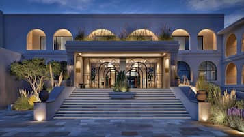 A grand hotel entrance with a central staircase, arched windows, and a well-lit facade.