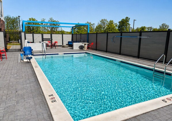 A rectangular swimming pool with a blue border, a blue and white deck area, and a black fence. - Tru By Hilton Richmond Northwest (Richmond)