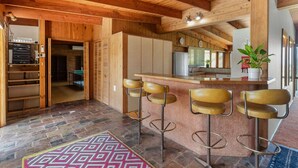 Eine moderne Küche mit Holzausstattung, einer Bar mit Hockern und einem gemusterten Teppich.