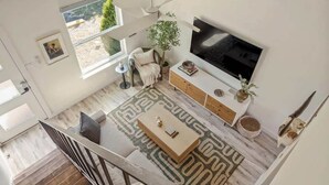 Una sala de estar moderna con un televisor grande, un sofá, una mesa de centro y una alfombra estampada.