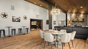A modern dining area with a round table and chairs, a black leather sofa, and a stone fireplace. - The Zoo Barn! Pool, Hot Tub, Bball/Pkbl, Theater (Spring Green)