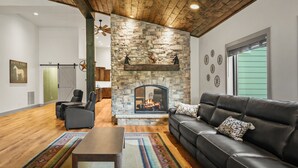 A living room with a stone fireplace, leather sofa, and a wooden ceiling. - The Zoo Barn! Pool, Hot Tub, Bball/Pkbl, Theater (Spring Green)