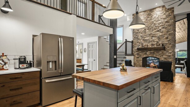 A modern kitchen with a central island, stainless steel appliances, and a stone accent wall. - The Zoo Barn! Pool, Hot Tub, Bball/Pkbl, Theater (Spring Green)