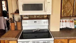 A kitchen with a white microwave, stove, and oven, wooden cabinets, and a wooden countertop. - This 1889 house is one of the most historic and unique places in Canon city. (Cañon City)