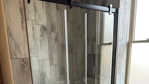 A shower with a glass door, wooden wall tiles, and a small rug on the floor. - This 1889 house is one of the most historic and unique places in Canon city. (Cañon City)