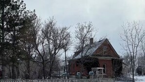 A red brick house with a wooden porch, surrounded by a wooden fence and trees. - This 1889 house is one of the most historic and unique places in Canon city. (Cañon City)