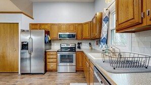 A modern kitchen with wooden cabinets, stainless steel appliances, and a dish rack. - 1/2 Mi to Lake! Traverse City Retreat w/ Dock (Traverse City)