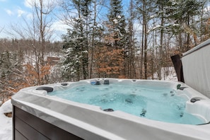 A hot tub surrounded by snow-covered trees and a clear sky. - L'Orignal et L'Érable by Tremblant Platinum (La Conception)